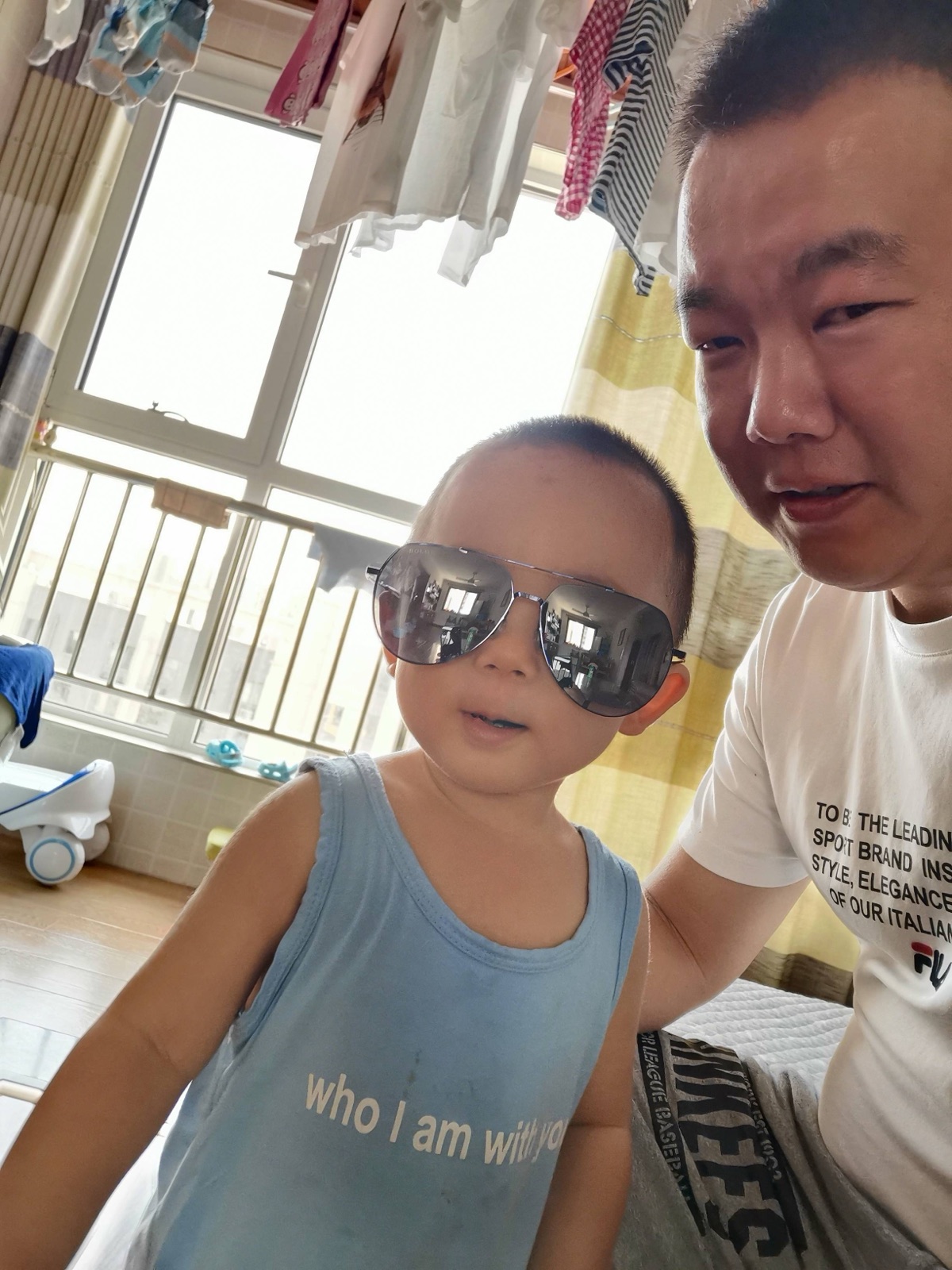 2019 年 8 月 14 日日记所附照片，刘一和爸爸自拍，身后晾着衣服
